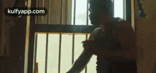 a man is standing in front of a window holding his arm .