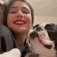 a woman is smiling while holding a dog in her lap .