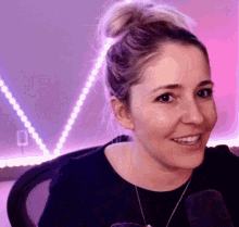 a woman with a bun on her head is smiling in front of a microphone