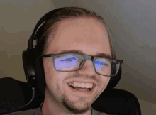 a man wearing headphones and glasses is smiling
