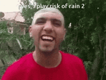 a man in a red shirt is smiling and saying `` yes , i play risk of rain 2 ''
