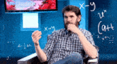 a man in a plaid shirt sits in front of a sony tv