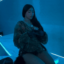 a woman in a camo jacket and fishnet shorts is sitting on a car with her arms outstretched