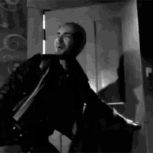 a black and white photo of a man holding a woman 's hand in a room .