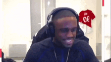 a man wearing headphones is smiling in front of a red jersey with the number 30 on it