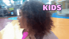 a woman in a pink shirt with the word kids on her head