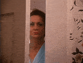 a woman in a blue robe is peeking out of a doorway