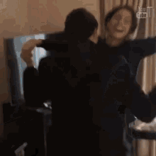 a woman is holding a man in her arms in a room .