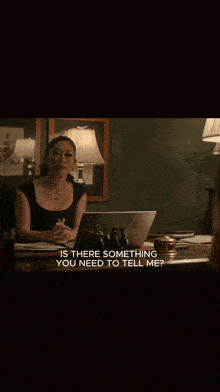 a woman is sitting at a desk with a laptop and talking on the phone