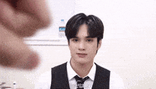 a young man in a suit and tie is talking to another person .