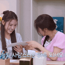 two women sitting at a table with korean writing on the bottom right