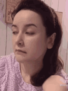 a close up of a woman 's face with a purple shirt on