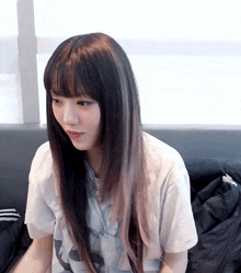 a girl with long black hair and bangs is wearing a white t-shirt
