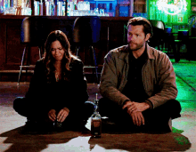a man and a woman sit on the floor with a bottle of jack daniel 's
