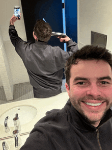a man taking a selfie with a gun in front of a bathroom mirror