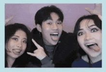 a man and two women are sticking their tongues out in a photo booth .