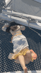 a woman in a white dress is laying on a net on a boat