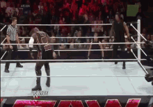 two wrestlers are in a wrestling ring with a referee in the background .