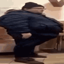 a very fat man wearing a hat and glasses is standing with his hands in his pockets .