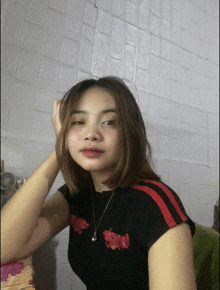 a young woman wearing a black shirt with red stripes and a necklace with the word devil on it