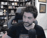 a man with a beard is sitting in front of a microphone and wearing a shirt that says ff3