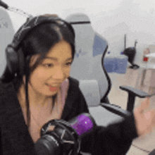 a woman wearing headphones is sitting in front of a microphone in a chair .