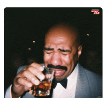 a man with a mustache is crying while holding a glass of whiskey