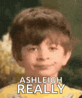 a young boy is smiling with the words `` ashleigh really '' written above him .