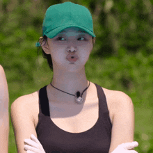 a woman wearing a green hat and a black tank top makes a funny face