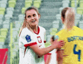 a female soccer player wearing a number 4 jersey is hugging another female soccer player