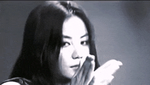 a woman with long hair is covering her mouth with her hands