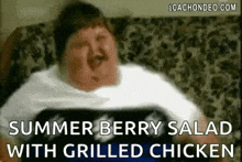 a man is sitting on a couch eating a salad with grilled chicken .