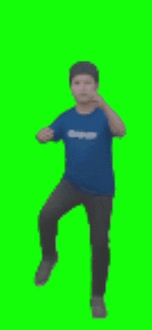a man in a blue shirt is standing on one leg on a green screen .
