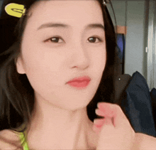 a close up of a woman 's face with a yellow g on her hair clip