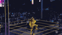 a wrestler in a yellow outfit stands in a wrestling ring with a referee