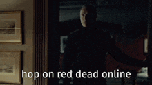 a man is standing in a dark room with the words hop on red dead online written on the screen .