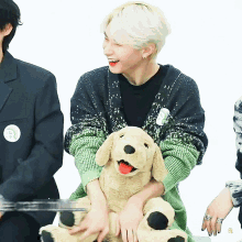 a man in a green and black sweater is holding a stuffed dog with the letter p on it