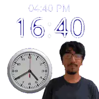 a man wearing glasses stands next to a clock that says 16:40 pm