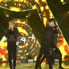 two men are standing on a stage singing into microphones and dancing .