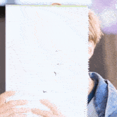 a man with blonde hair is covering his face with a book .