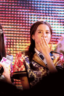 a woman covering her mouth while holding a microphone that says joyol on it