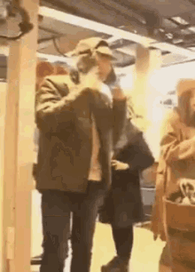 a man in a hat is smoking a cigarette while standing next to a woman in a black coat .
