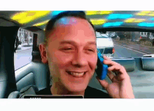 a man is talking on a cell phone in a car