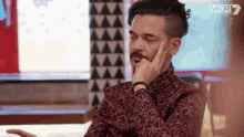 a man sitting in front of a mkr television screen