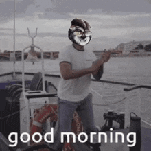 a man wearing a clown mask is dancing on a boat with the words `` good morning '' written below him .