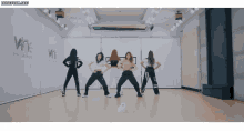 a group of girls are dancing in a dance studio with the words wne entertainment on the wall