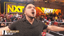 a man in a wrestling ring with the nxt logo behind him