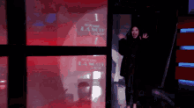 a woman in a black coat stands in front of a red sign that says ' la nuit '