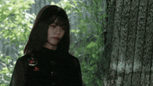 a woman with blood on her face stands next to a tree