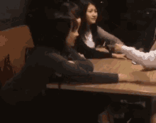a group of women are sitting at a table talking to each other